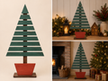 Handmade slatted wooden Christmas tree on red planter stand, shown freestanding as a statement Christmas decoration next to a fireplace and fairy lights
