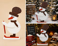 Handmade wooden skiing snowman decoration in large size, with top hat, scarf and skis, shown freestanding as a Christmas display piece