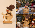Handmade wooden skiing snowman decoration in small size, with top hat, scarf and ski pole, shown freestanding as a Christmas display piece
